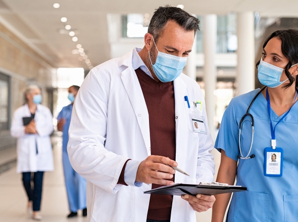 Two medical professionals walking in hospital with clipboard. Exponent provides data-driven insights to advance medical science. 