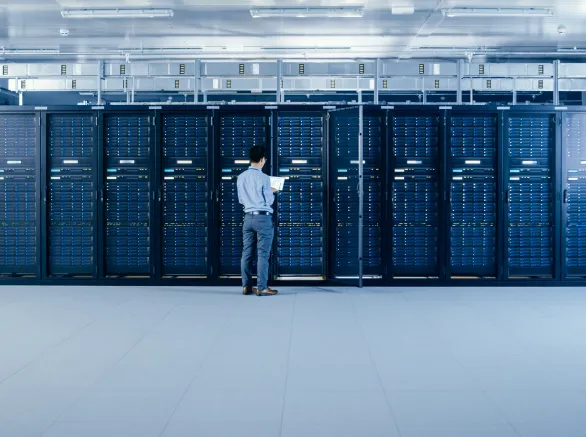 In the Modern Data Center: IT Engineer Standing Beside Open Server Rack Cabinets, Does Wireless Maintenance and Diagnostics Procedure with a Laptop.
