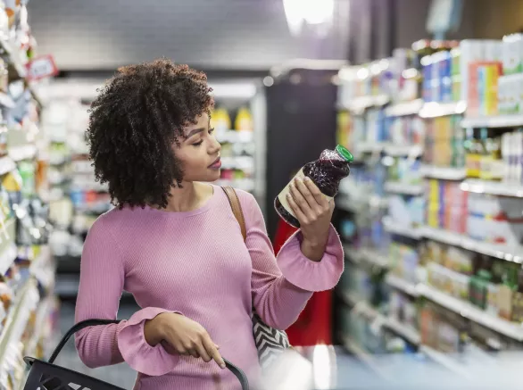 Young woman looks at bottle in store