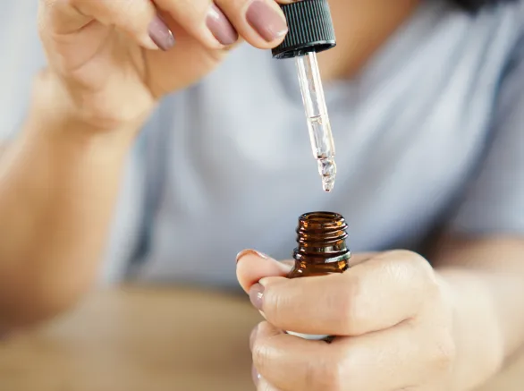 Closeup woman dropping essential oil on her hand
