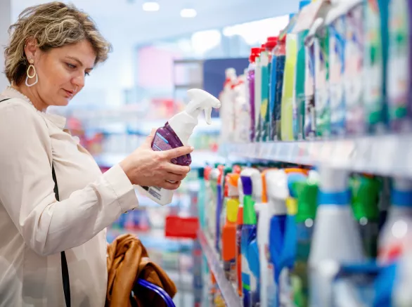 Woman choosing domestic cleaning product by the supermarket shelf