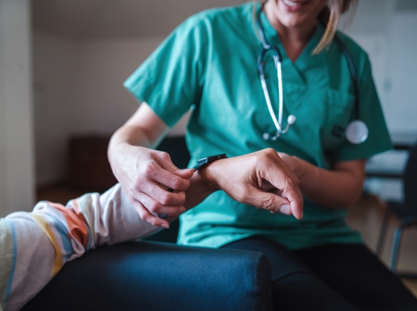 Smartwatch for health care. A woman from the medical health system wears a smartwatch for remote monitoring of vital signs on an elderly person