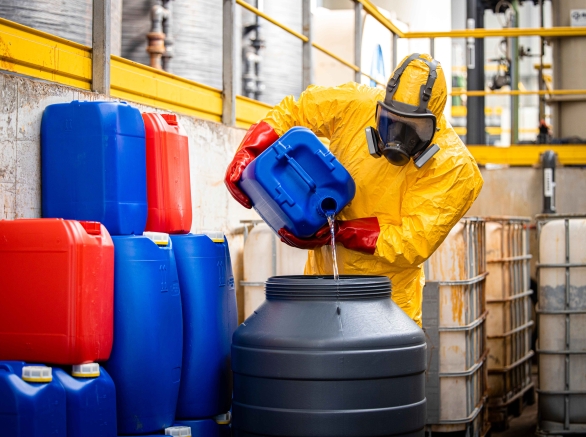 Chemical worker in yellow protection suit and gas mask making sulfuric acid for industry.