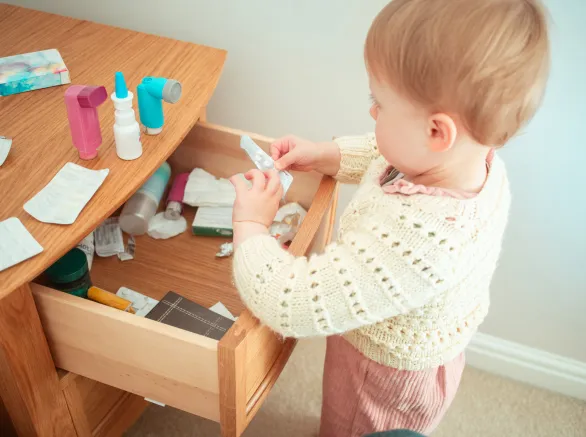 Toddler looking through a bedside cabinet full of prescription medicines