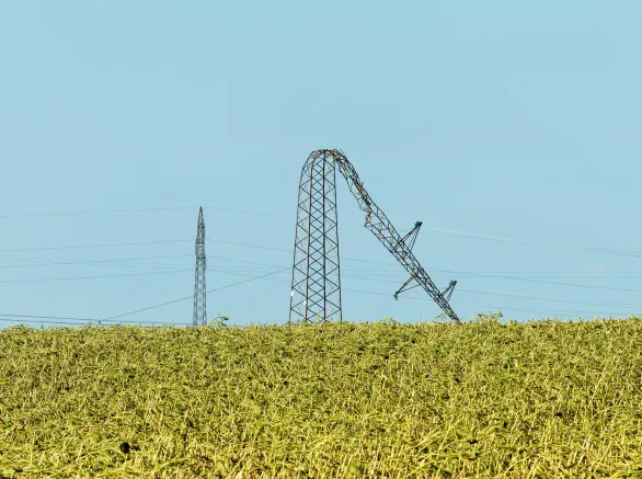 Bent over electricity pylon after strong summer storm, climate change consequences