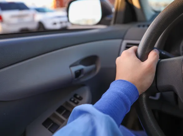 hand gripping a steering wheel while driving a car, focused and in control