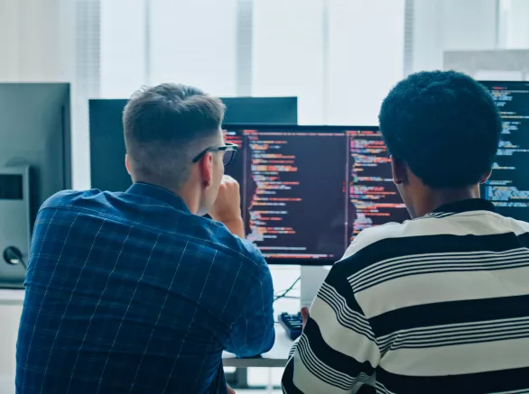 software developers meeting on multiple computer screens displaying programming code