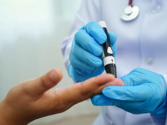 Asian woman self testing to check blood sugar level diabetes by digital lancet on finger at home.