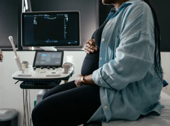 Pregnant woman holding her belly during a prenatal exam.