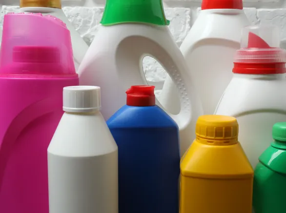  House cleaning supplies on a wooden table against a brick wall background 