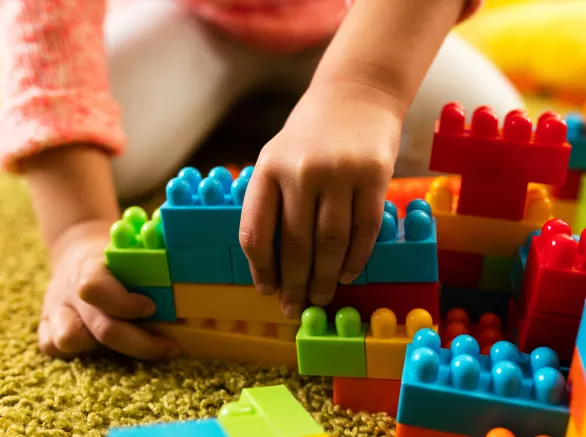child playing with toy blocks on the carpet