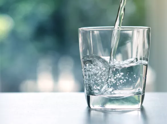 Close up the pouring purified fresh drink water from the bottle on table in living room 