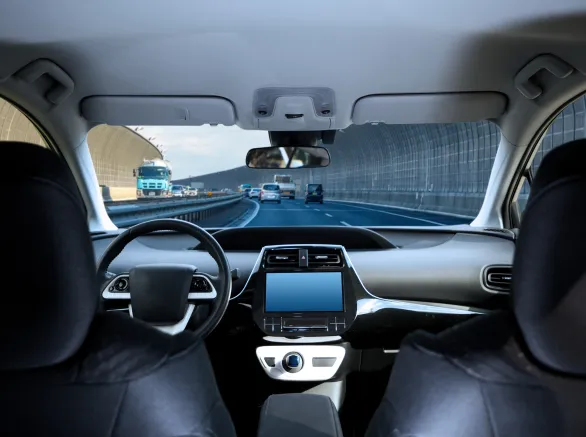 Cockpit of driverless car driving on highway viewed from rear seat.