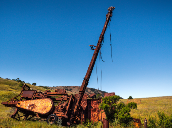 Rusty abandoned well and equipment in the middle of a hillside field