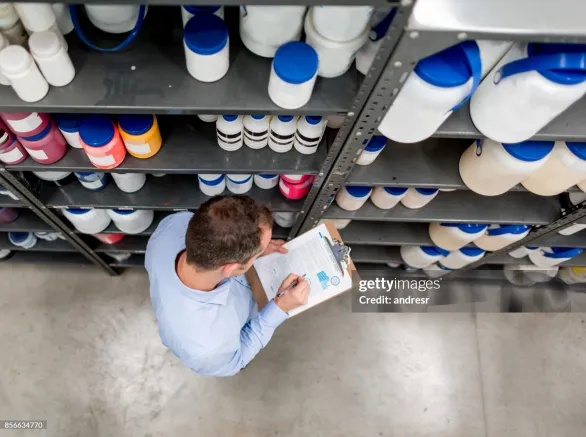 Man doing an inventory at a chemical warehouse and writing on a clipboard - business concepts