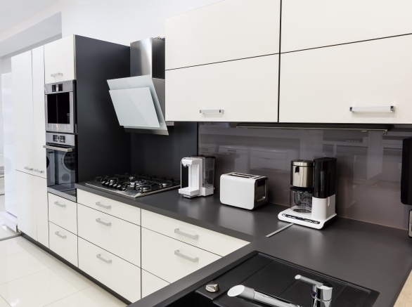 A modern hi-tech kitchen with white cabinets and black countertops