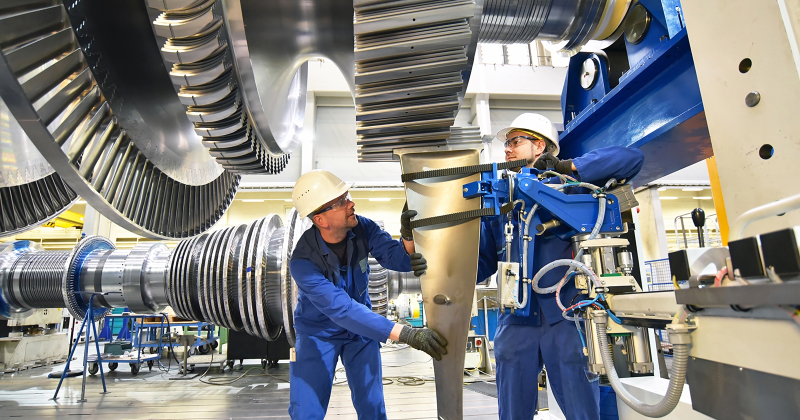Two workers evaluate equipment on factory floor. Exponent conducts risk and safety analysis of mechanical engines. 