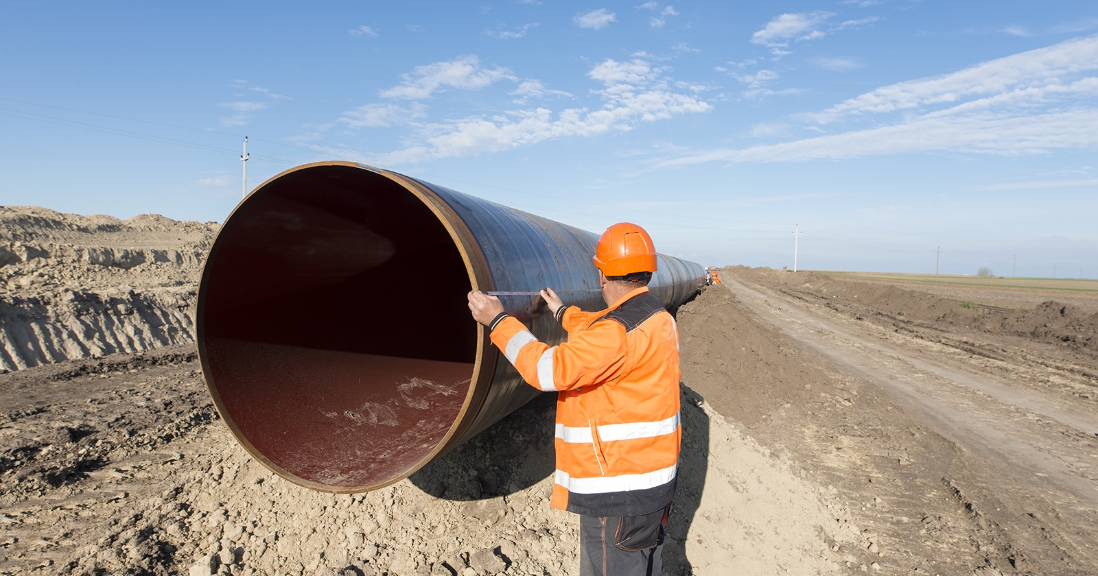 A person inspects a large oil pipeline before installation. Exponent materials engineers help improve the safety & performance of pipelines. 