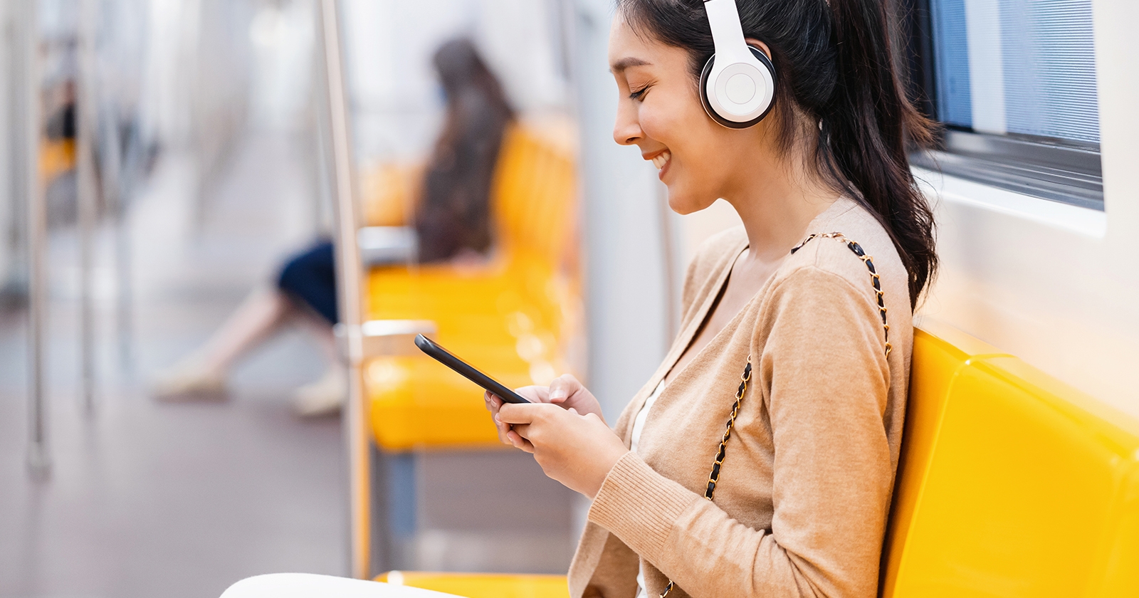 A person sitting in a train wearing headphones. Exponent helps manufacturers improve the quality and performance of consumer products.