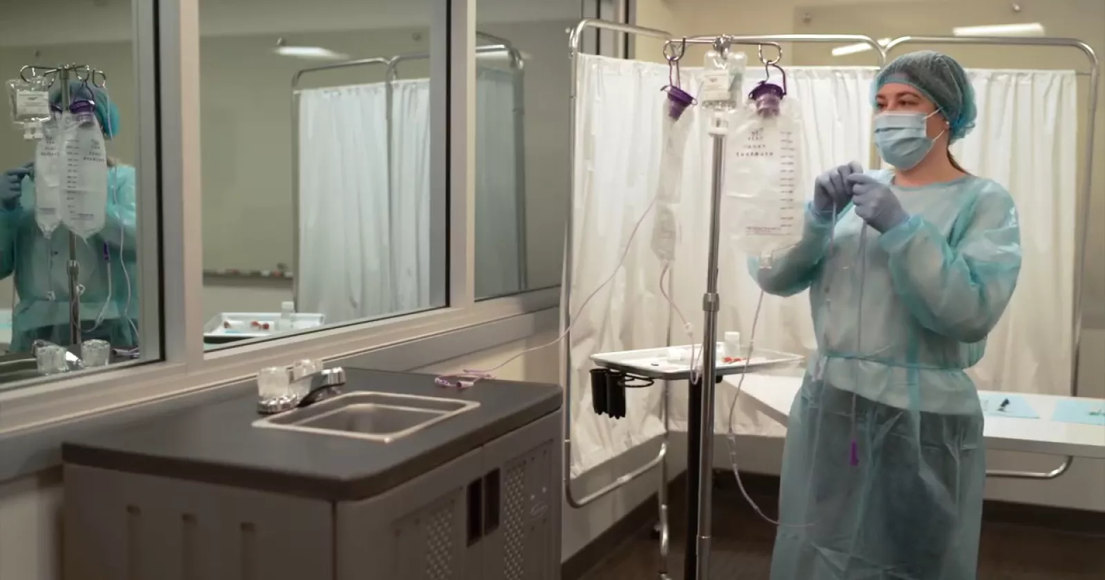 medical personnel hanging an iv bag wearing ppe