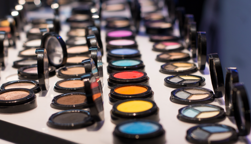 Makeup compacts with pressed powder in a rainbow of colors and shades lined up on a display shelf