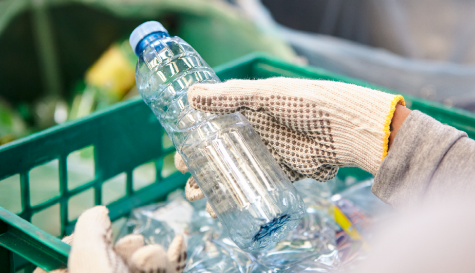 Close up of someone sorting through a crate of plastic bottles at a recycling facility