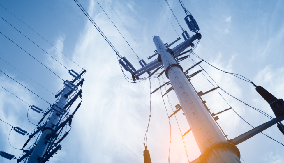 View of two utility poles and wires from the ground against a clear blue sky