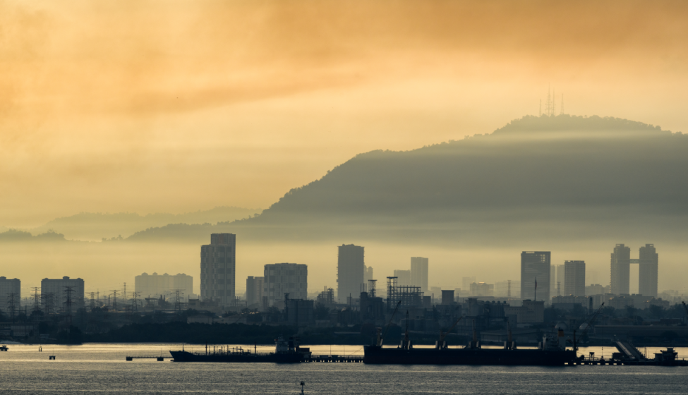 Hazy view, across a bay, of a city with mountain in background