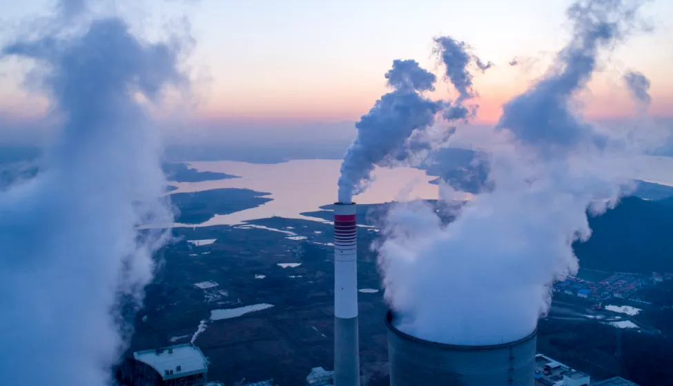 Smoke releases from a smoke stack at a chemical plant overlooking a body of water