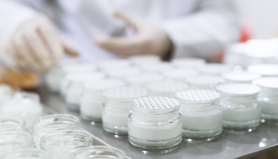 Cosmetic product in a glass jar being sealed by hand