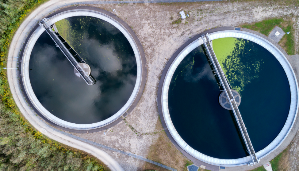 Bird's eye view of 2 circular wastewater treatment plants separating green pollutants from water