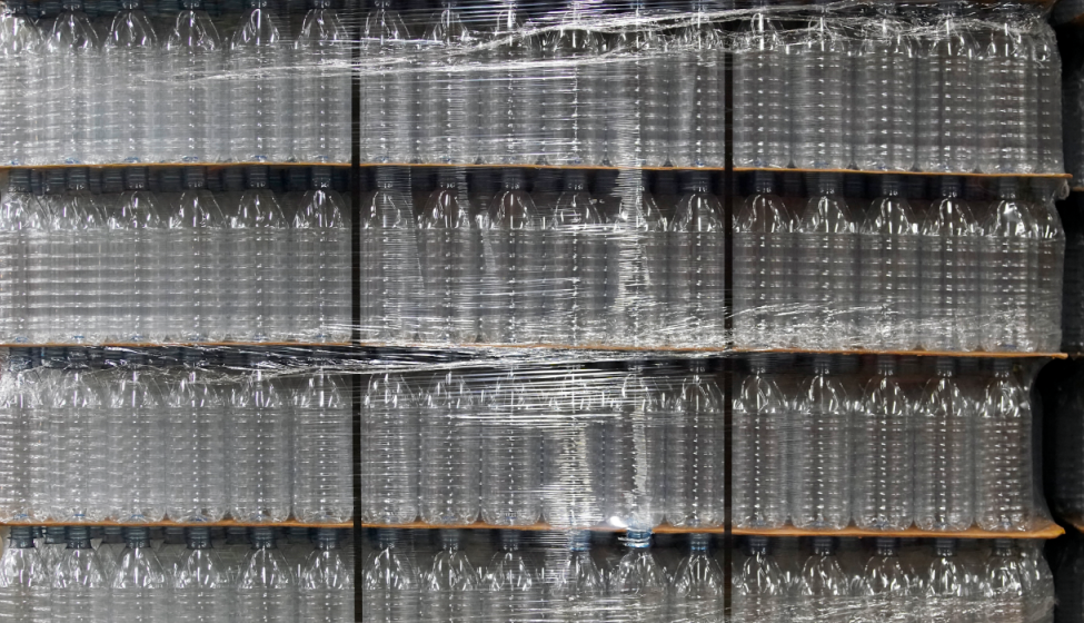 Plastic bottles wrapped in plastic packaging stacked on shelves