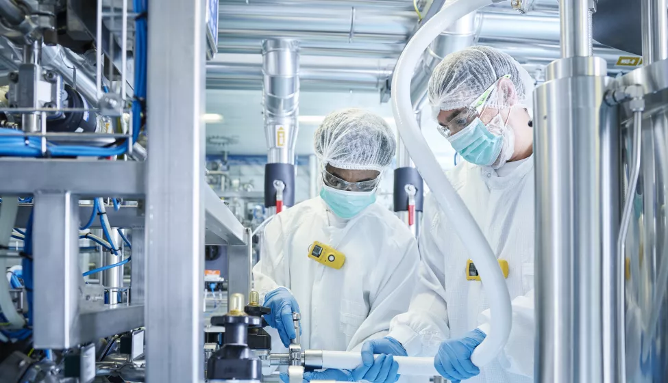 Two scientists wearing safety gear while operating machinery in a laboratory