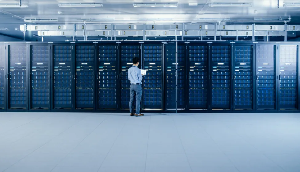 In the Modern Data Center: IT Engineer Standing Beside Open Server Rack Cabinets, Does Wireless Maintenance and Diagnostics Procedure with a Laptop.