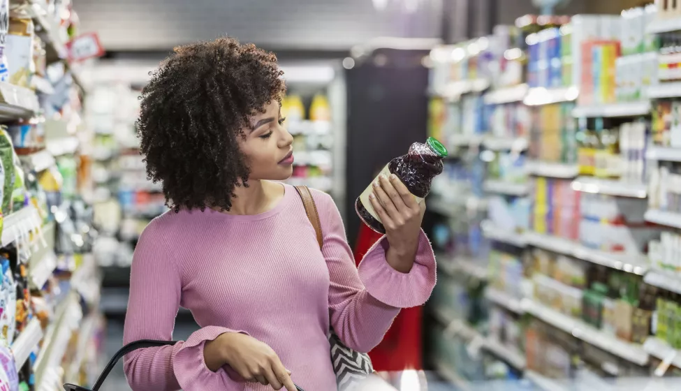 Young woman looks at bottle in store