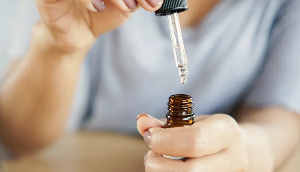 Closeup woman dropping essential oil on her hand
