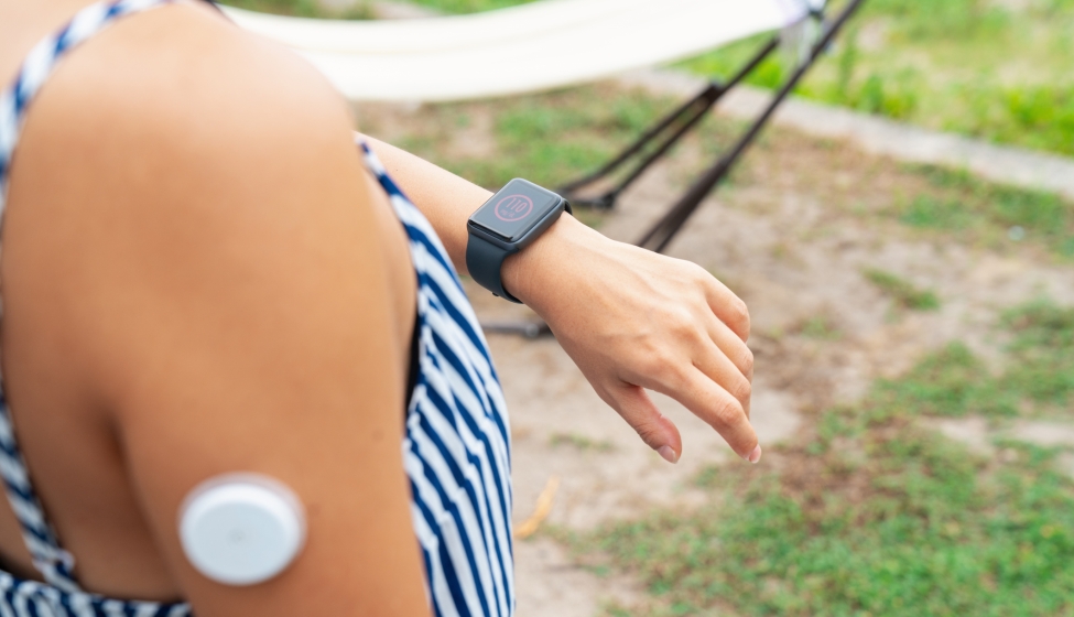 A person wearing a medical device on their arm, while checking their smart watch