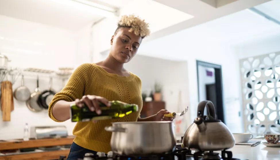 Person cooking on stove. Exponent helps manufacturers improve the safety and performance of all types of appliances and consumer products.