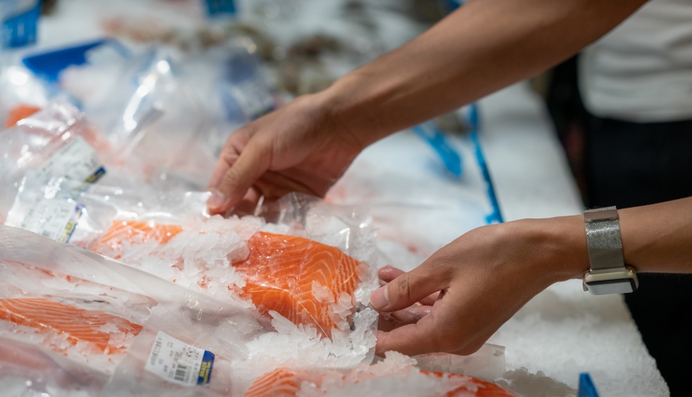 A man picks up a salmon fillet in the supermarket