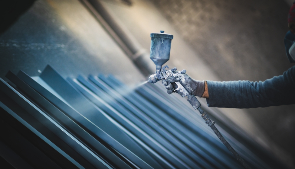 Man painting metal products with a spray gun
