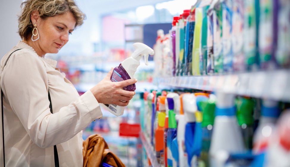 Woman choosing domestic cleaning product by the supermarket shelf