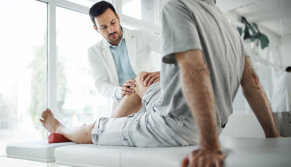 Senior man having his knee examined by a doctor.