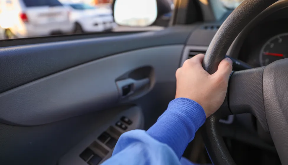hand gripping a steering wheel while driving a car, focused and in control