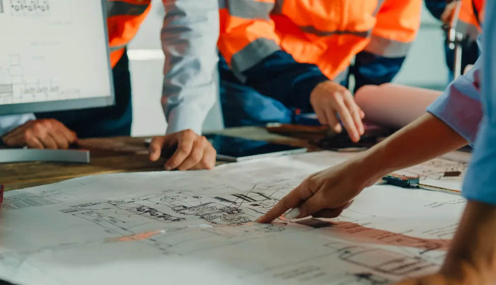 Closeup of team of industrial engineers meeting analyze machinery blueprints consult project on table in manufacturing factory. Working in manufacturing plant or production plant concept.