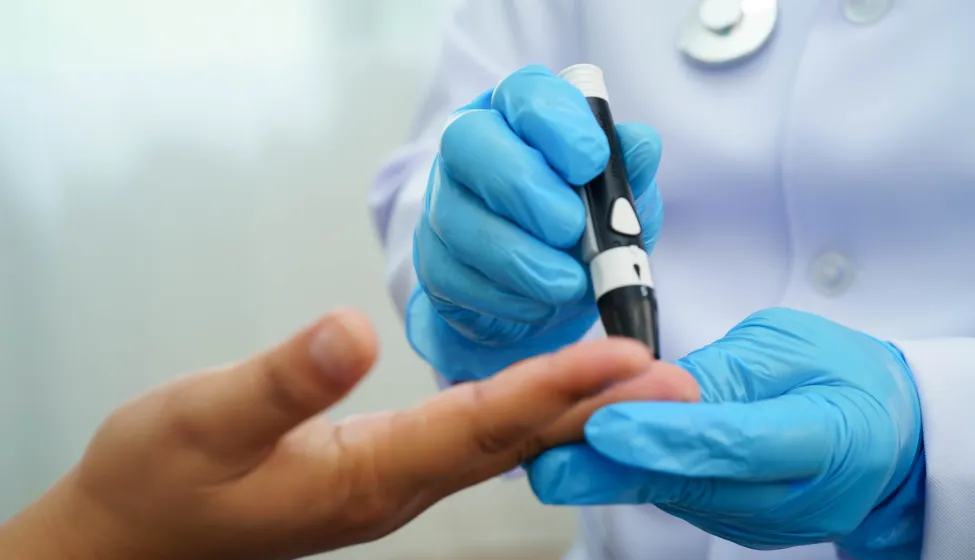 Asian woman self testing to check blood sugar level diabetes by digital lancet on finger at home.