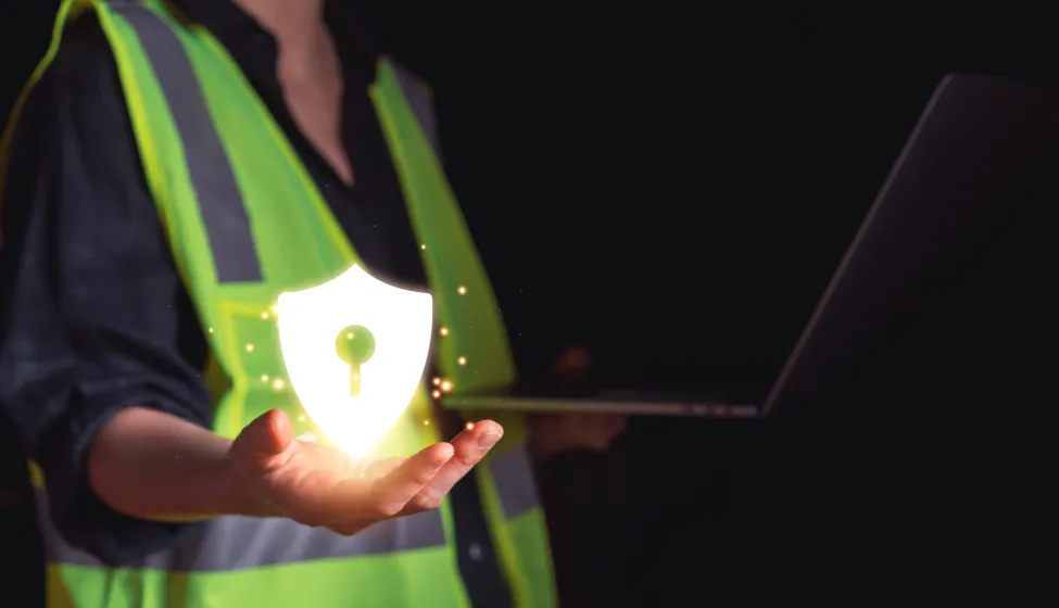Industrial worker in safety vest holding glowing shield icon with keyhole