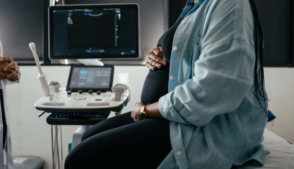 Pregnant woman holding her belly during a prenatal exam.