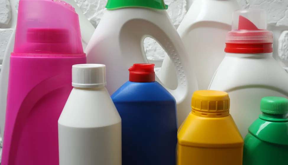  House cleaning supplies on a wooden table against a brick wall background 
