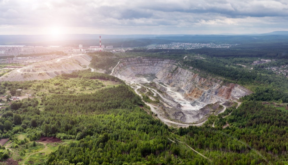 An aerial view of an open pit copper mine in a forested area. Exponent helps improve biodiversity and sustainability.