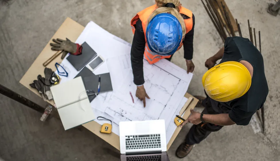 Two architects examining the blueprints on construction site